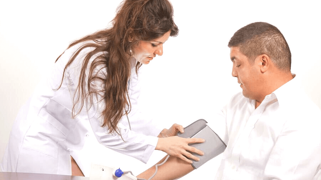 Woman in a white coat applying a blood pressure cuff to a middle aged man for a biometric screening event.