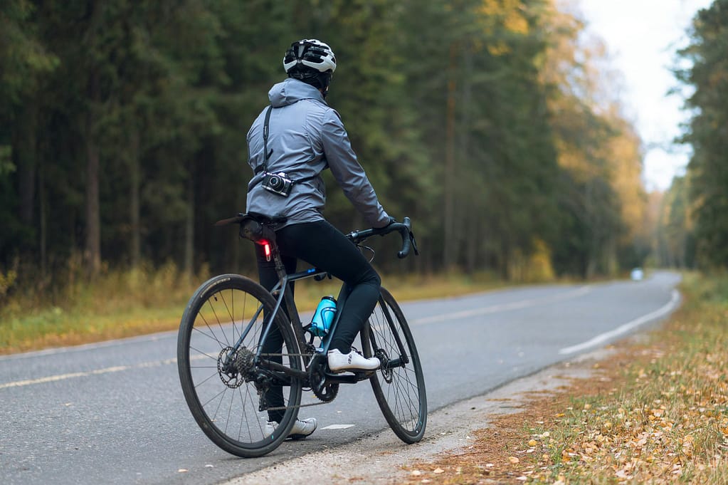 Person pausing on the side of the road to take in the fall scenery during a bike ride.