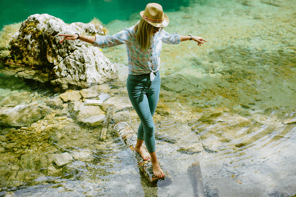 a woman balancing on rock in creek