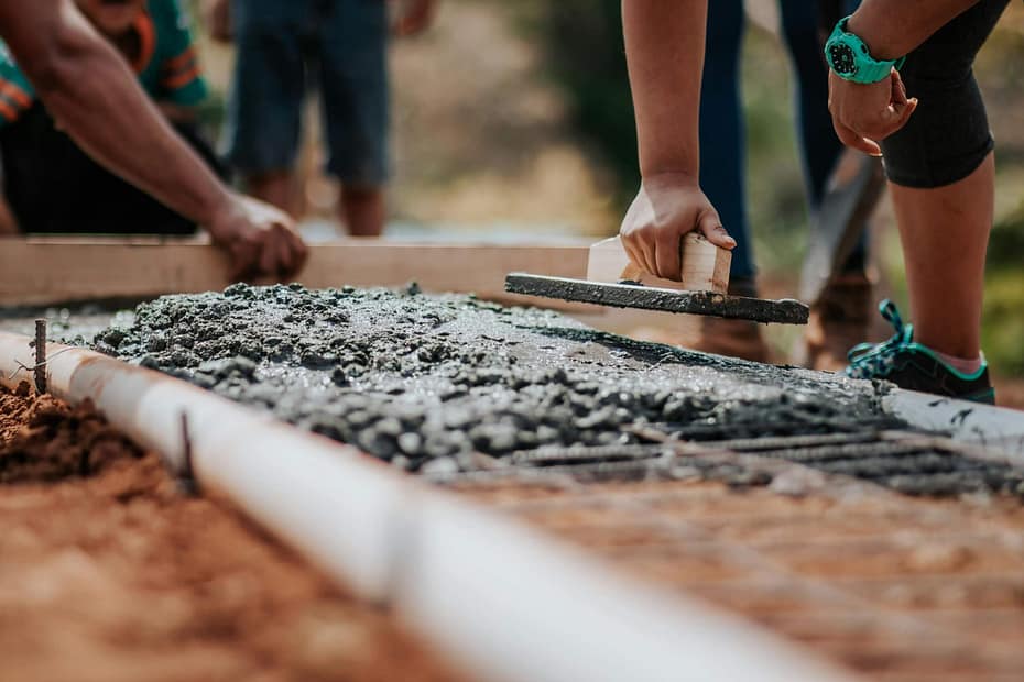 Construction workers smooth freshly poured concrete at a job site, demonstrating a practical, hands-on wellness initiative designed to support the health, safety, and well-being of blue-collar employees.