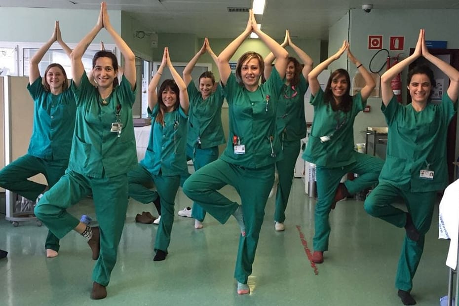 Group of medical professionals in blue scrubs going yoga in a hallway of the medical building.
