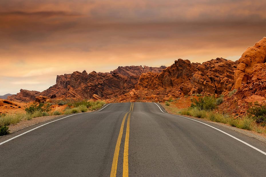 Open road winding through a dramatic desert landscape at sunrise, symbolizing the employee journey and helping organizations navigate smarter decisions through employee benefits surveys and workplace wellness insights.