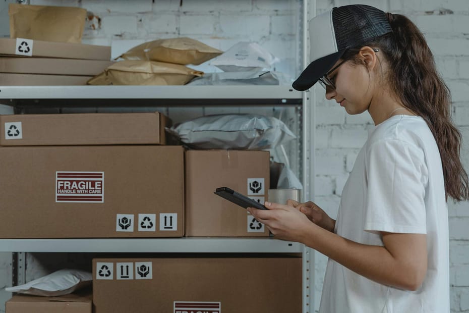 Warehouse employee uses a handheld device to manage packages and inventory in a logistics facility, illustrating how workplace wellness programs can support large, distributed workforces across warehouses and operational locations.