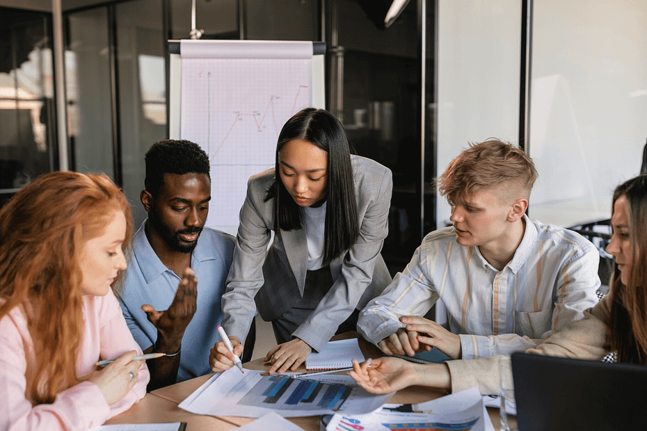 Group of employees sitting closely at a conference table marking a graphic sheet.